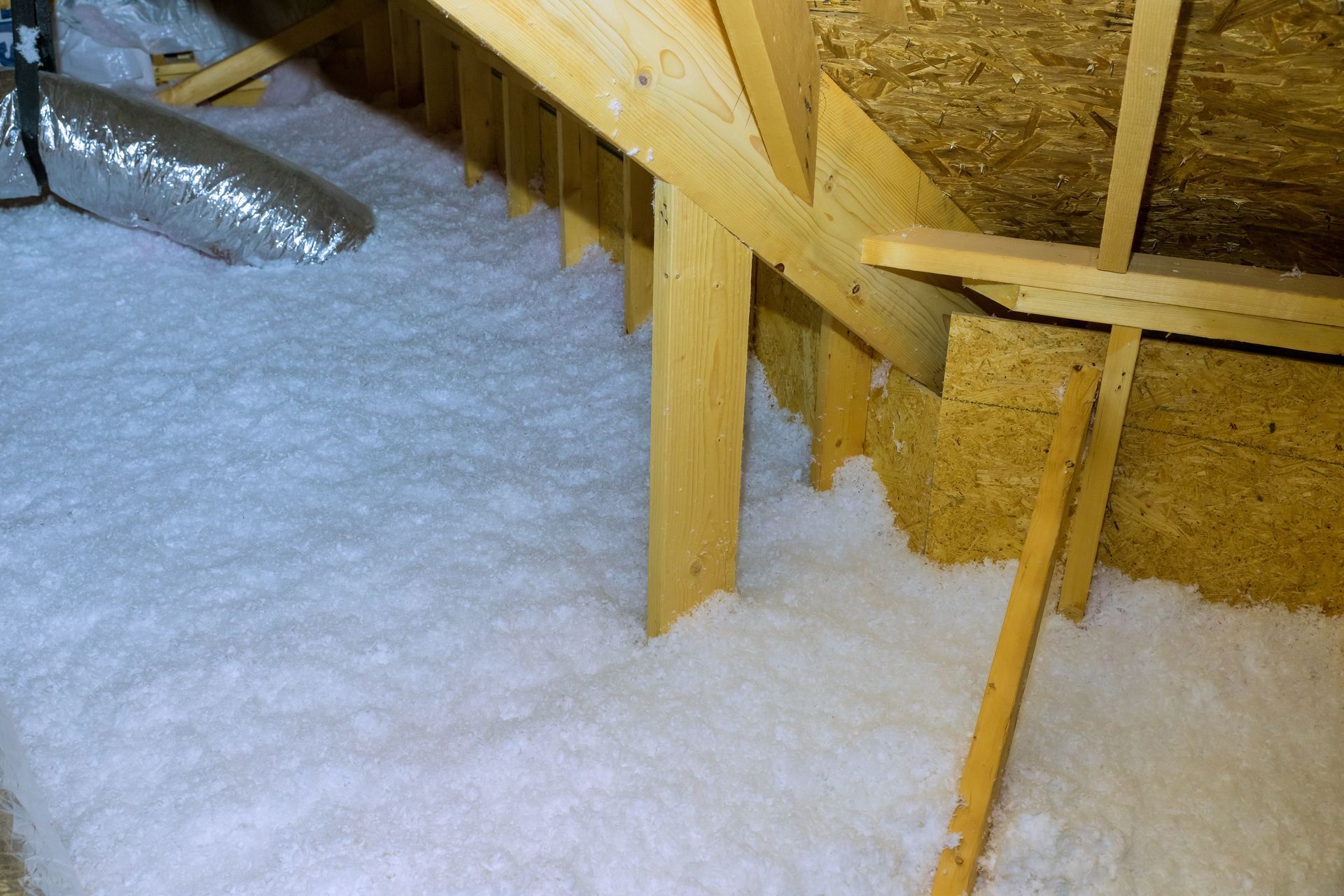 Insulated attic with wooden rafters and beams under a sloped roof