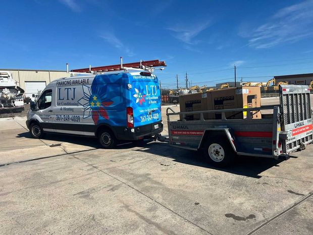 Blue LTJ work van towing a utility trailer in an industrial lot under a clear sky Blue LTJ work van towing a utility trailer in an industrial lot under a clear sky