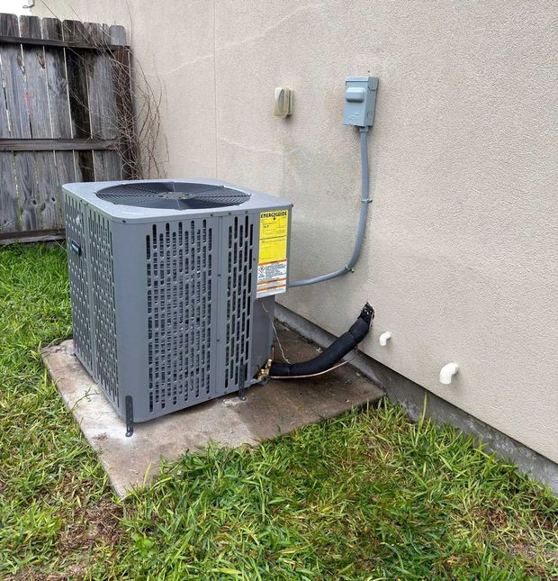 Outdoor AC unit beside a house wall with electrical conduit and grass yard nearby Outdoor AC unit beside a house wall with electrical conduit and grass yard nearby