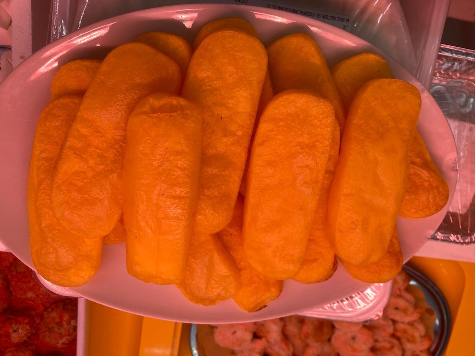 Un vassoio ovale pieno di bastoncini snack oblunghi, arancioni e soffici, è esposto in bella vista.