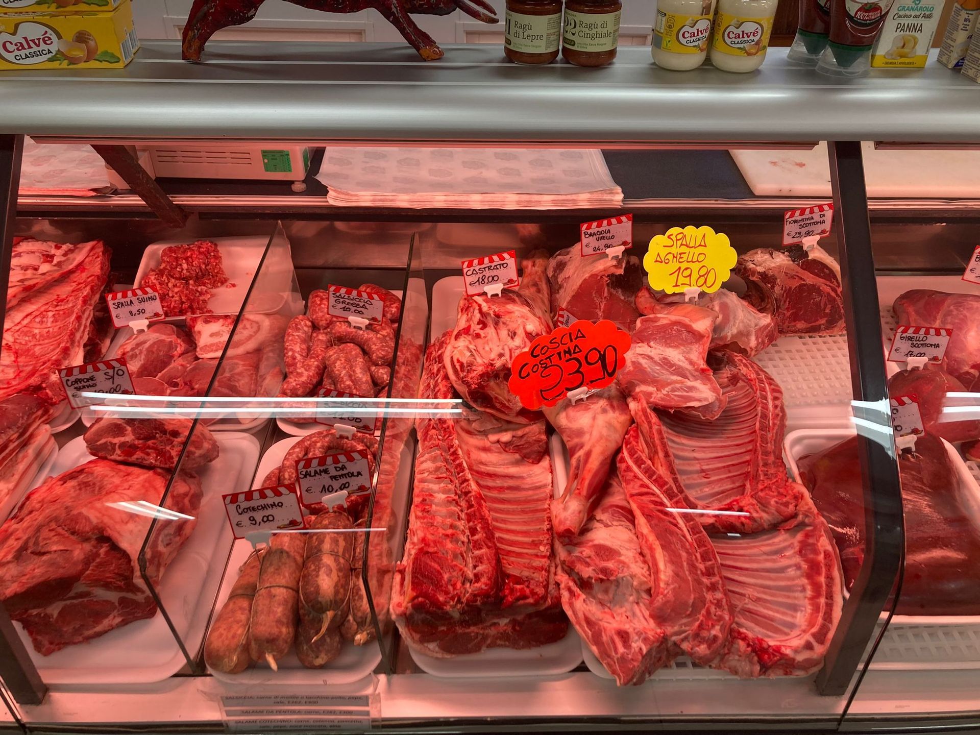 Una vetrina di una macelleria piena di vari tagli di carne rossa cruda, etichettati con piccoli cartellini del prezzo.