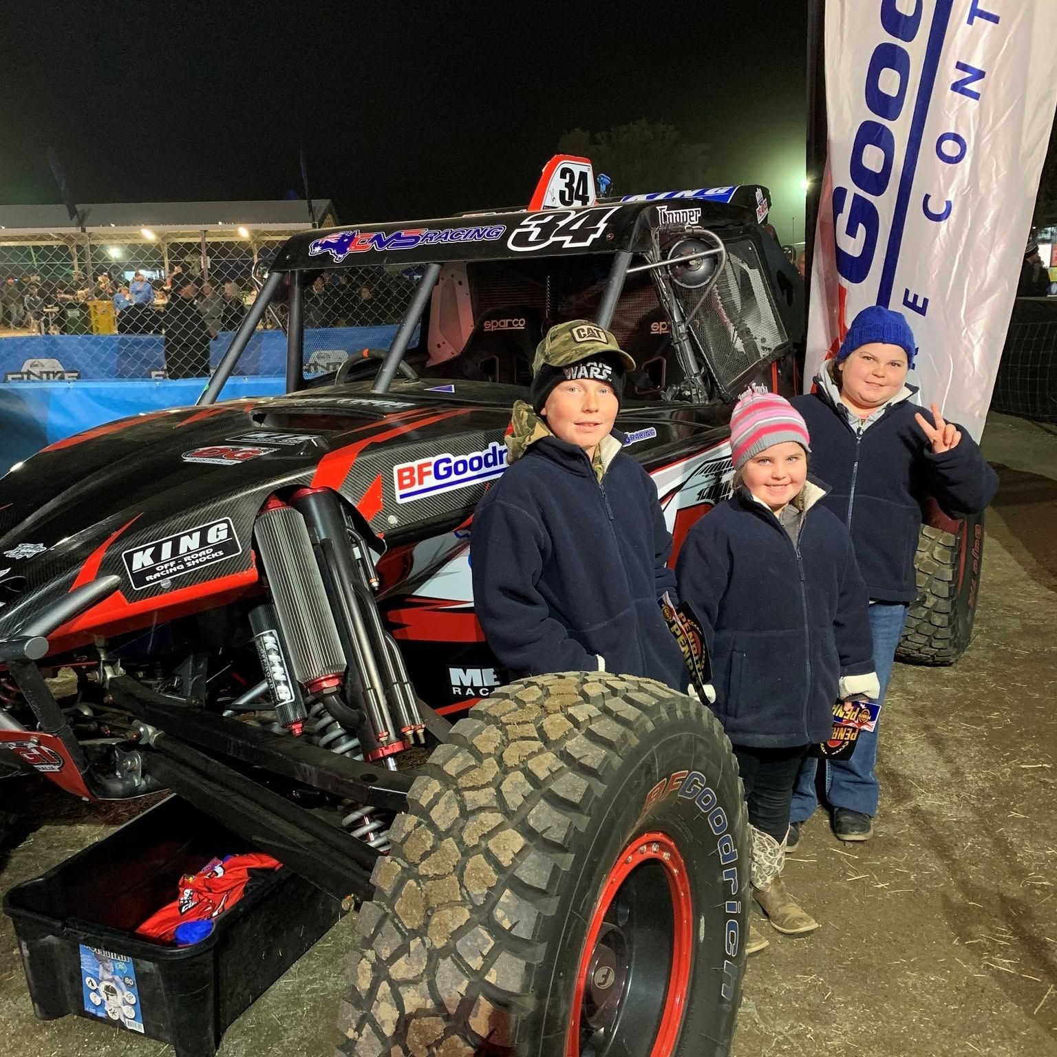 Three People Posing Beside a Black Off Road Race Truck at A Night Event — Blatherskite Park in Ilparpa, NT