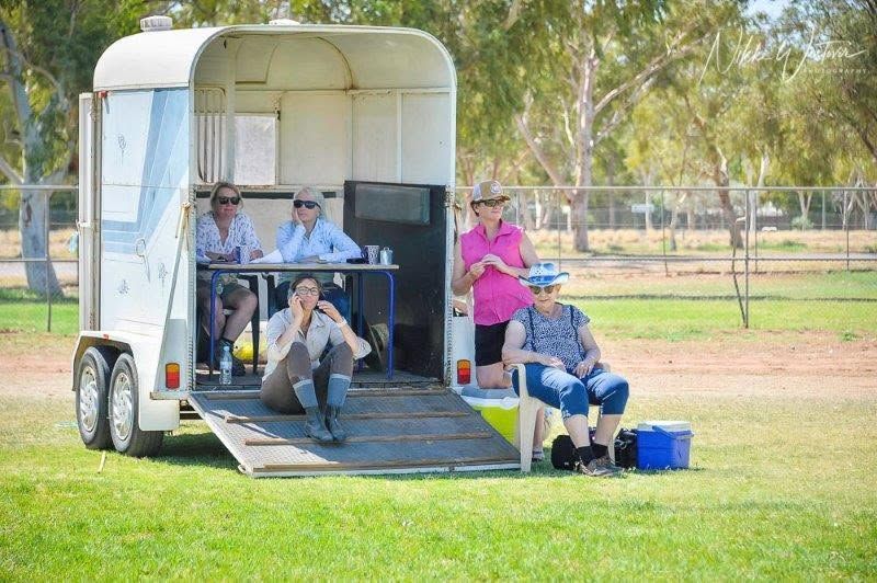 People Seated in And Around a White Trailer at A Grassy Park — Blatherskite Park in Ilparpa, NT
