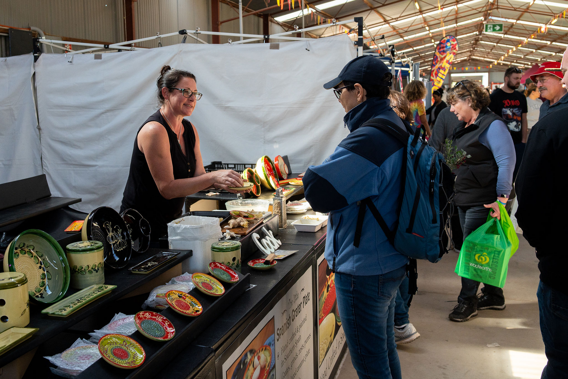 Vendor Serving Food to A Customer at An Indoor Market Stall with Colorful Produce on Display — Blatherskite Park in Ilparpa, NT