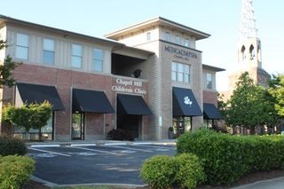 A large brick building with black awnings and a church in the background.