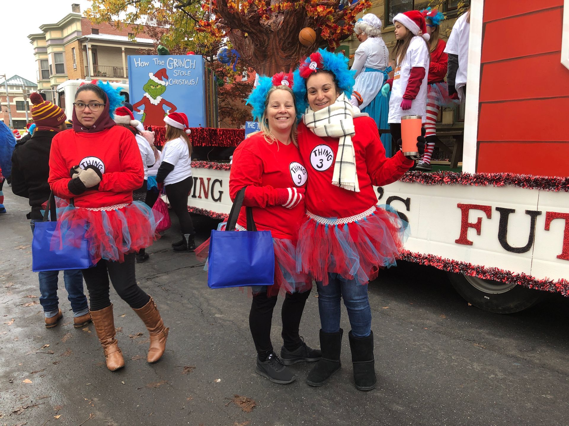 People in Cat in the Hat costumes at a parade, standing next to a float.