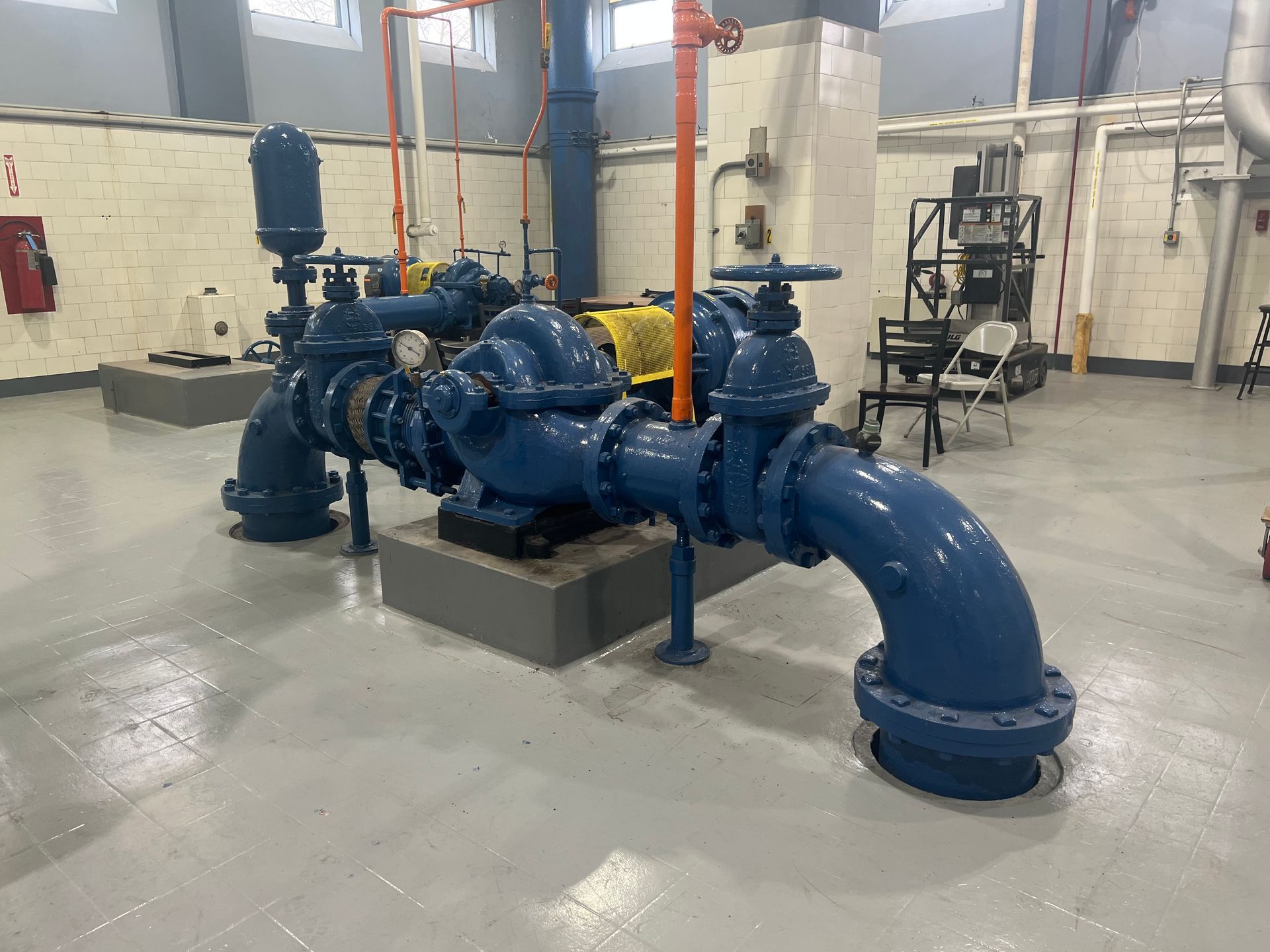 Blue water pump system in a gray-walled industrial space with exposed pipes and valves.