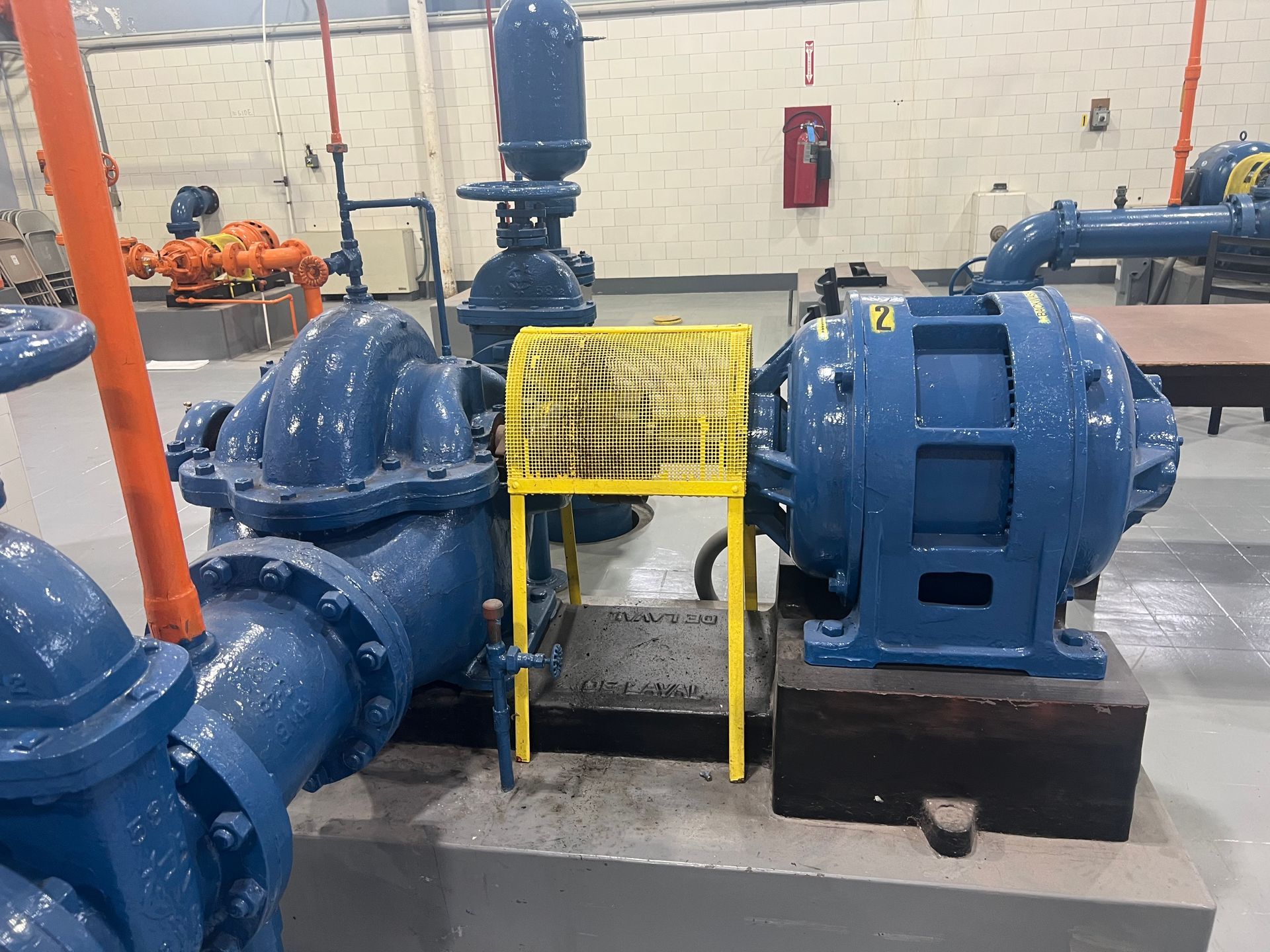 Blue pump and motor with yellow safety guard in an industrial setting.