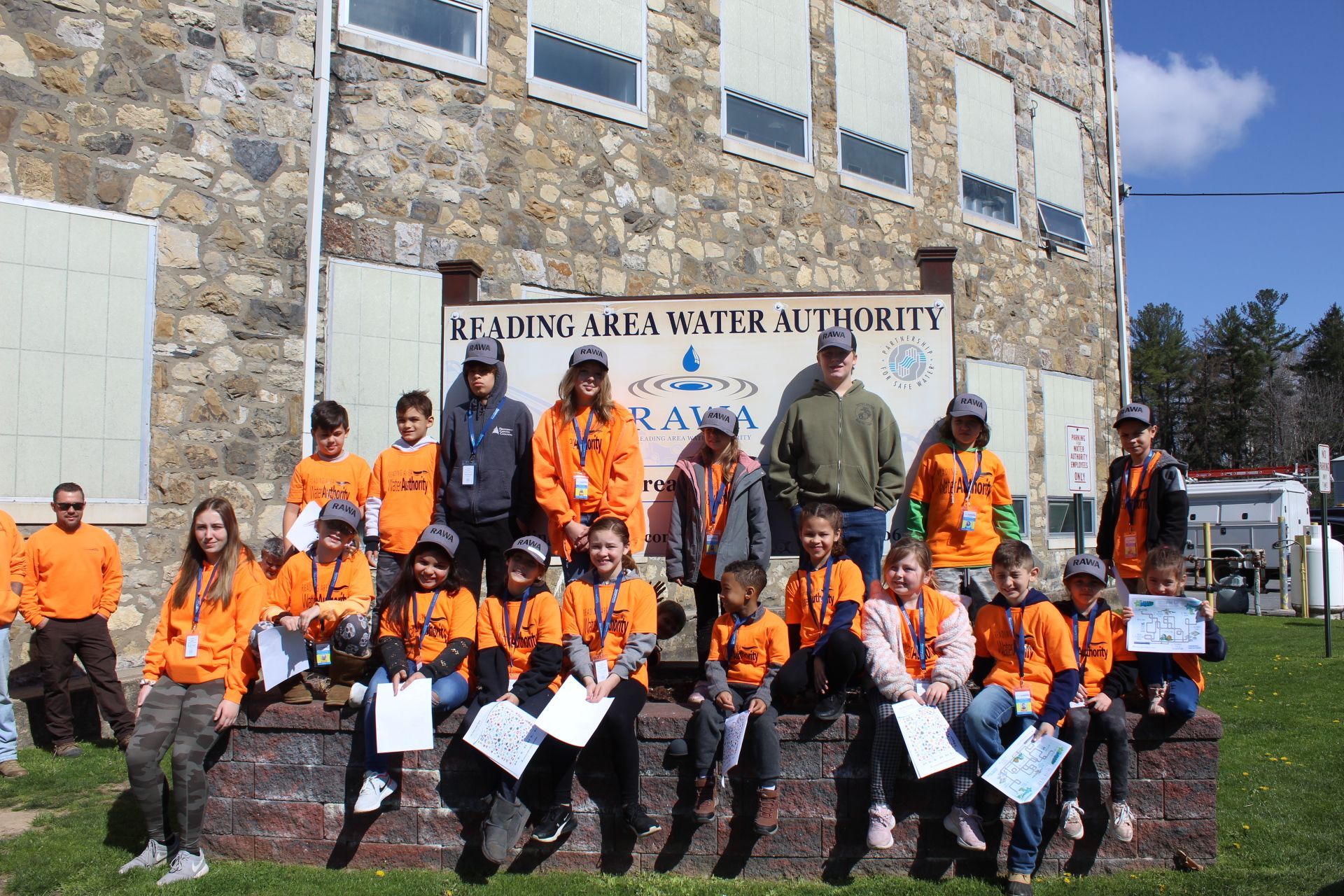 Group of kids in orange shirts posing in front of 