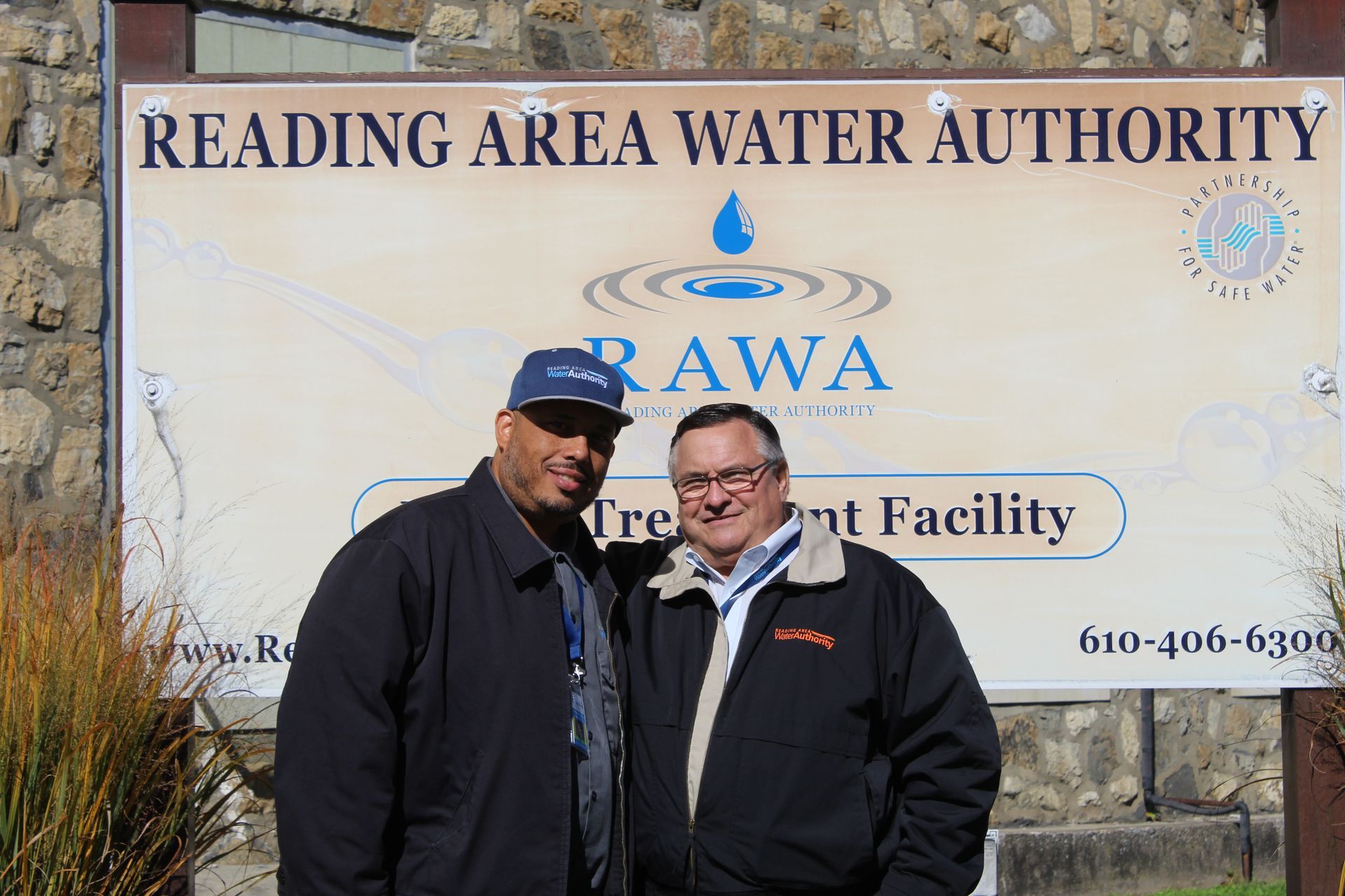 Two men stand in front of a sign for the Reading Area Water Authority Treatment Facility.