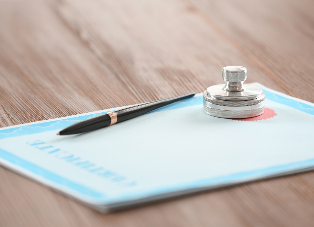 Certificate with pen and stamp on a wooden surface.