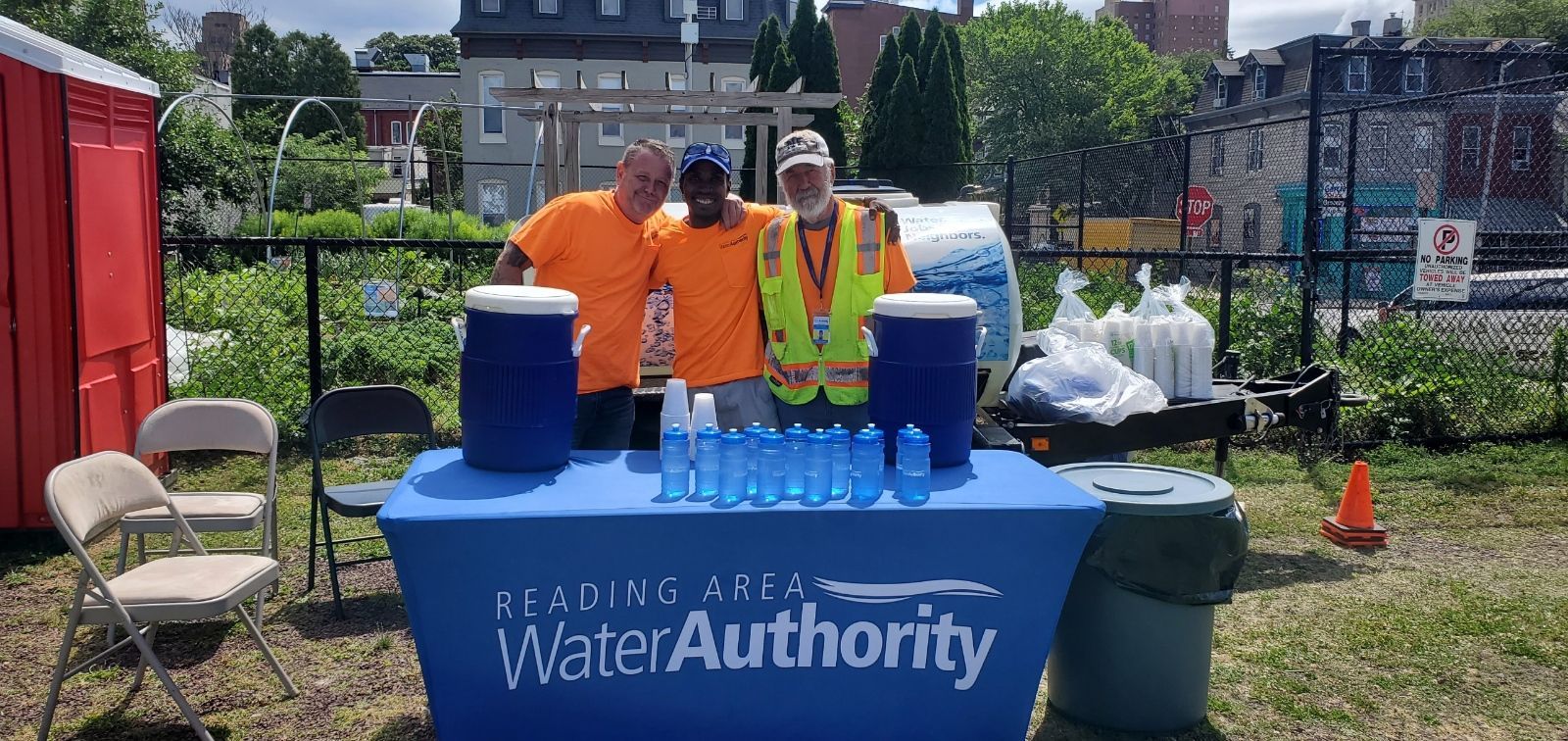 Three people smiling at a water station with a 