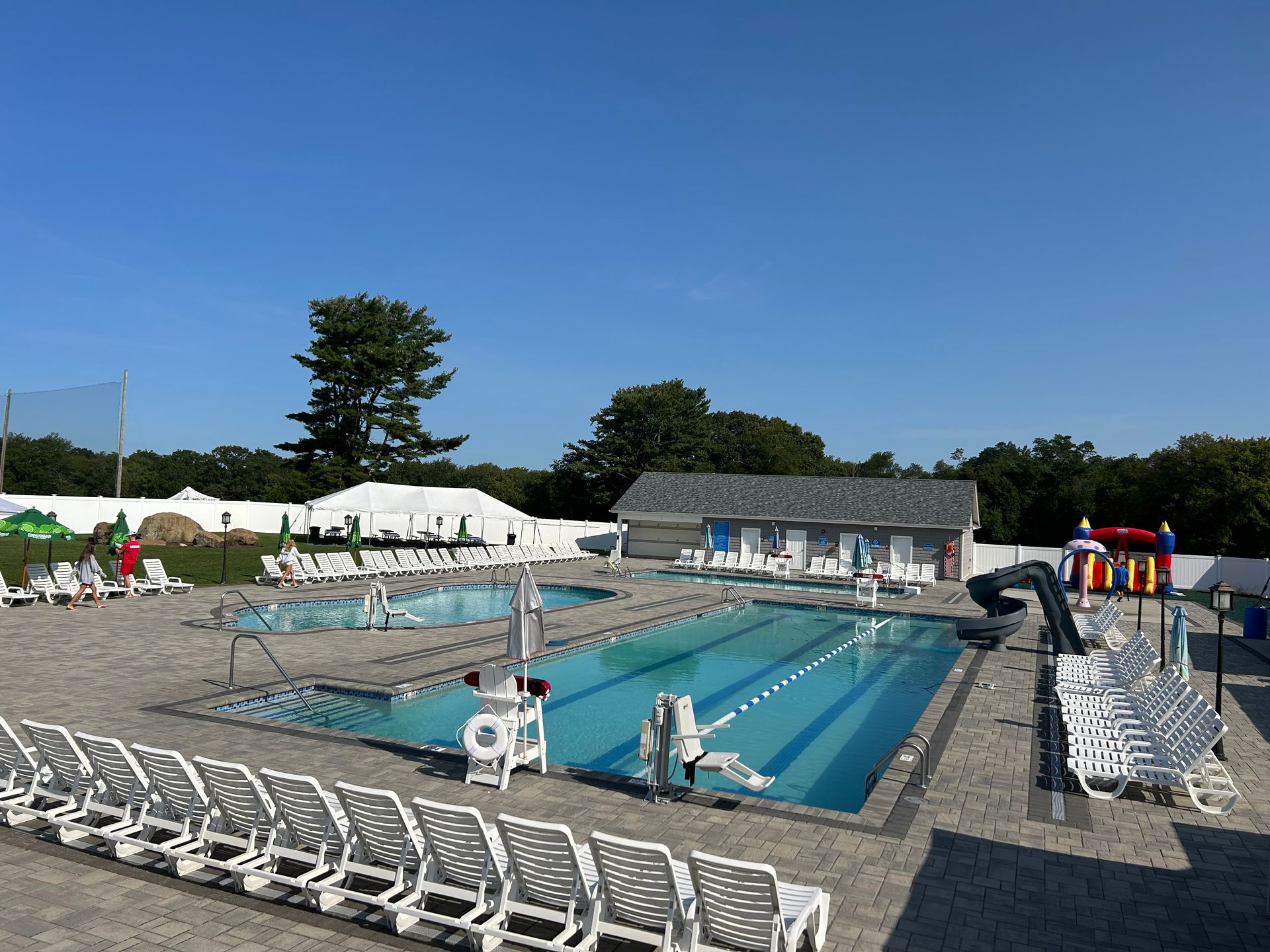 A large swimming pool surrounded by chairs and a bouncy house