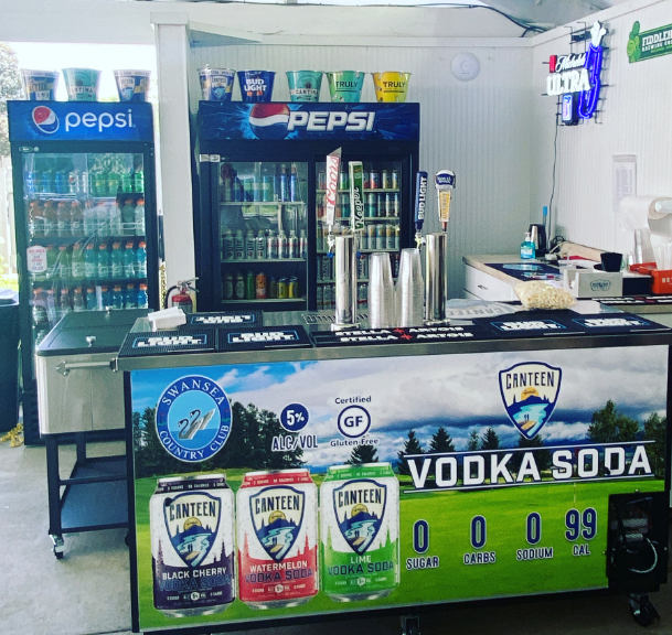 A pepsi fridge is behind a vodka soda cart