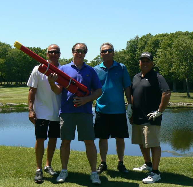 A group of men standing next to each other with one holding a large red object