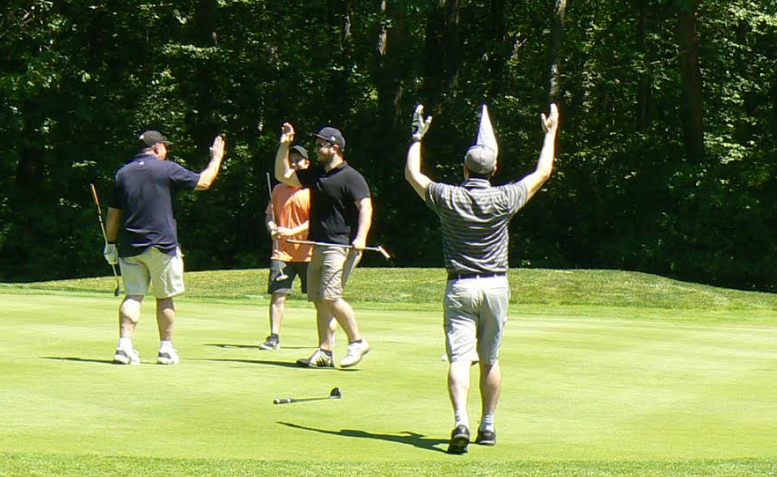A group of men are playing golf on a lush green field.