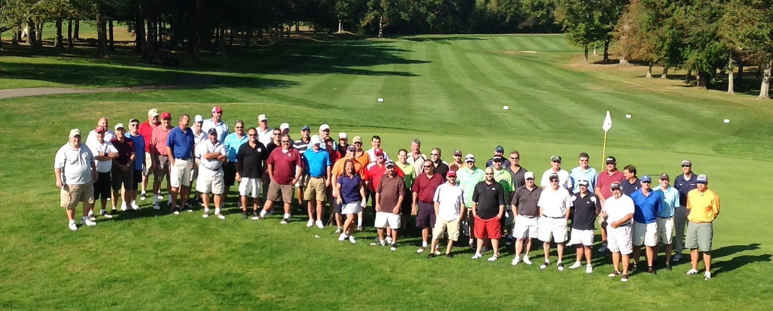 A large group of people are posing for a picture on a golf course.