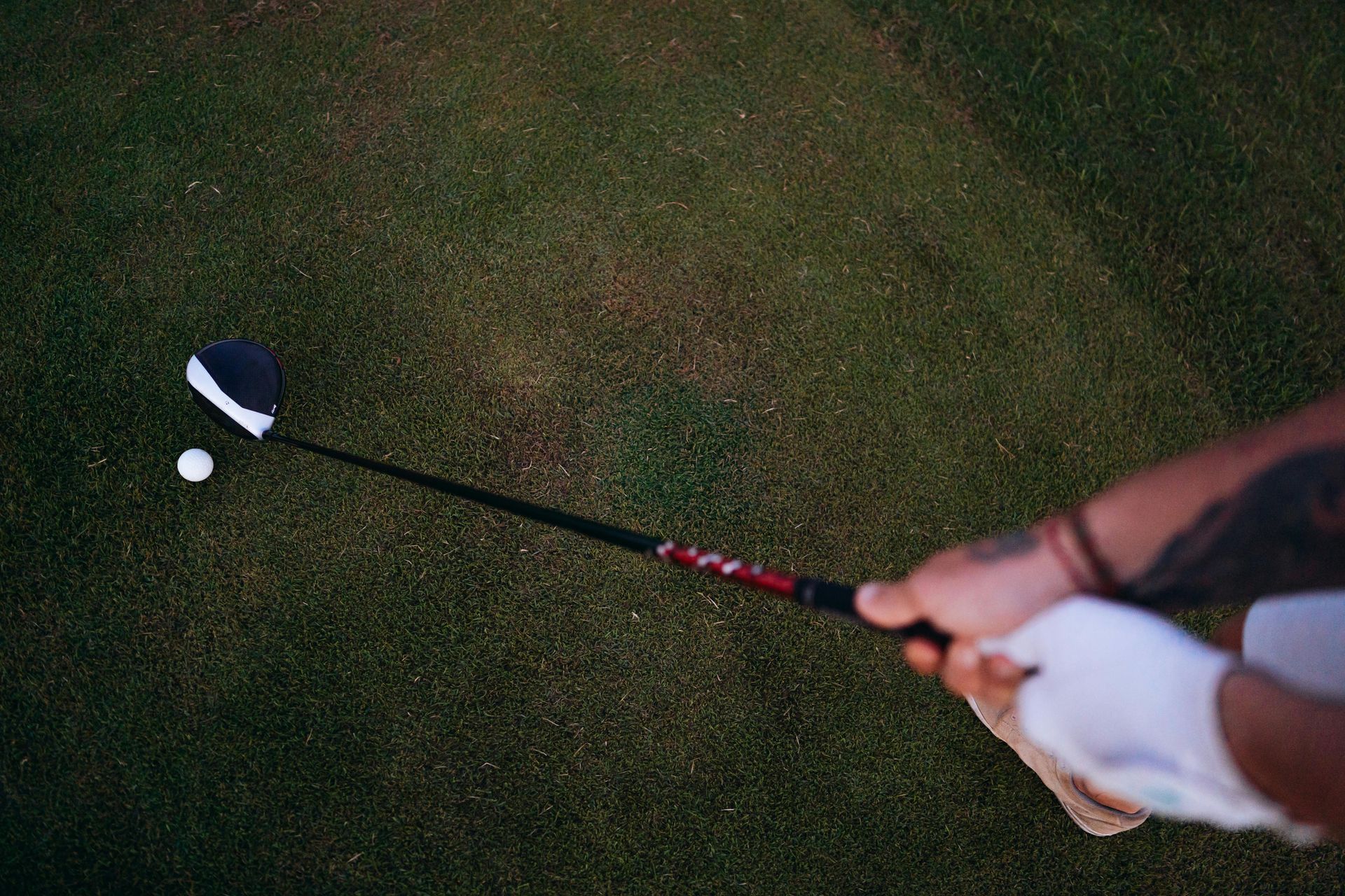 A person is swinging a golf club at a golf ball on a golf course.