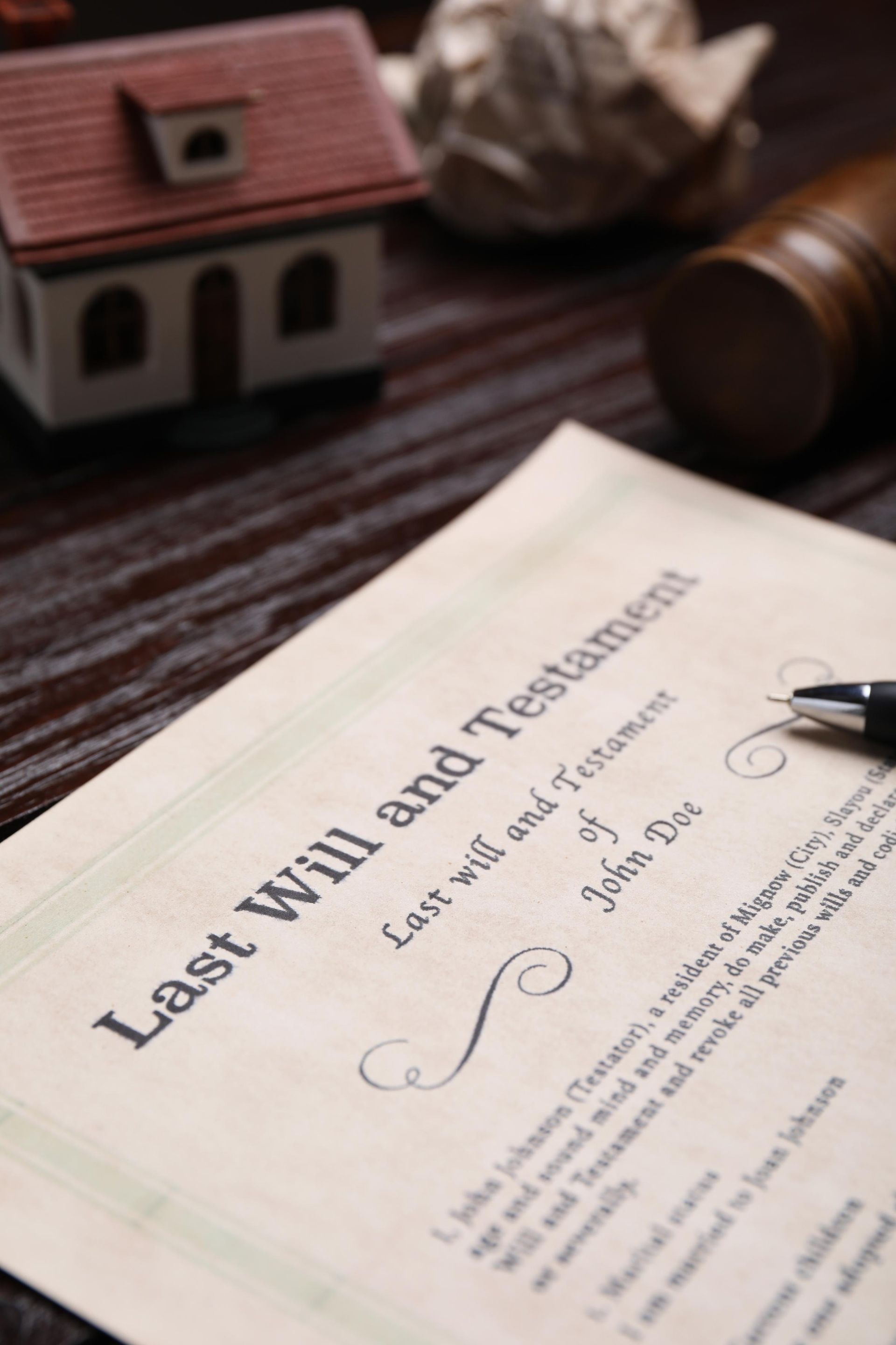 Last will and testament document beside a gavel and scales on a dark desk