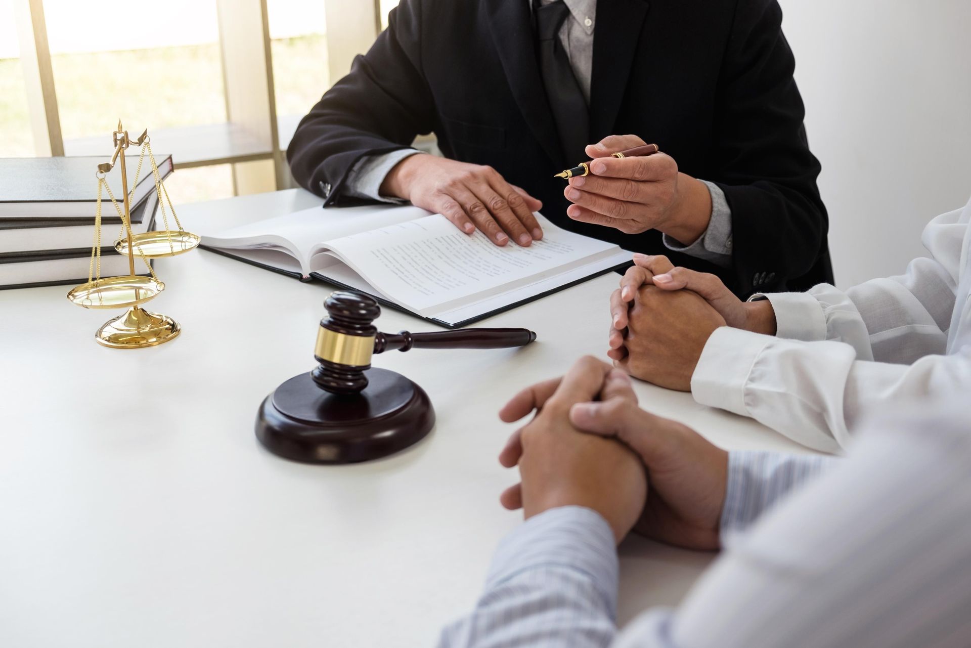 Lawyer discussing documents with clients at a desk, with a gavel and scales of justice nearby