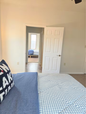 Bedroom view through open door showing bed by window.