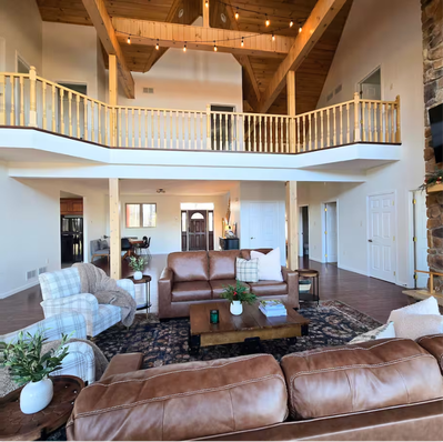 Living room with leather sofas, patterned rug, and loft balcony.