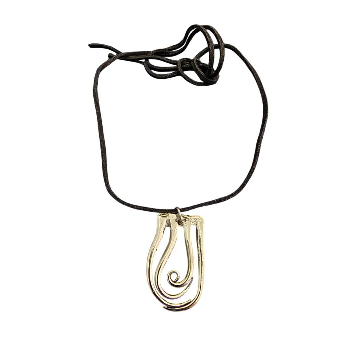 Collar de cordón negro con colgante dorado sobre fondo blanco