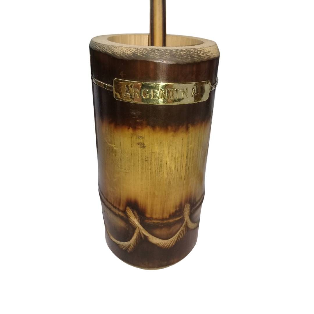 Taza tiki de cerámica marrón con banda dorada y diseño de cuerda decorativa, que sostiene una pajita.