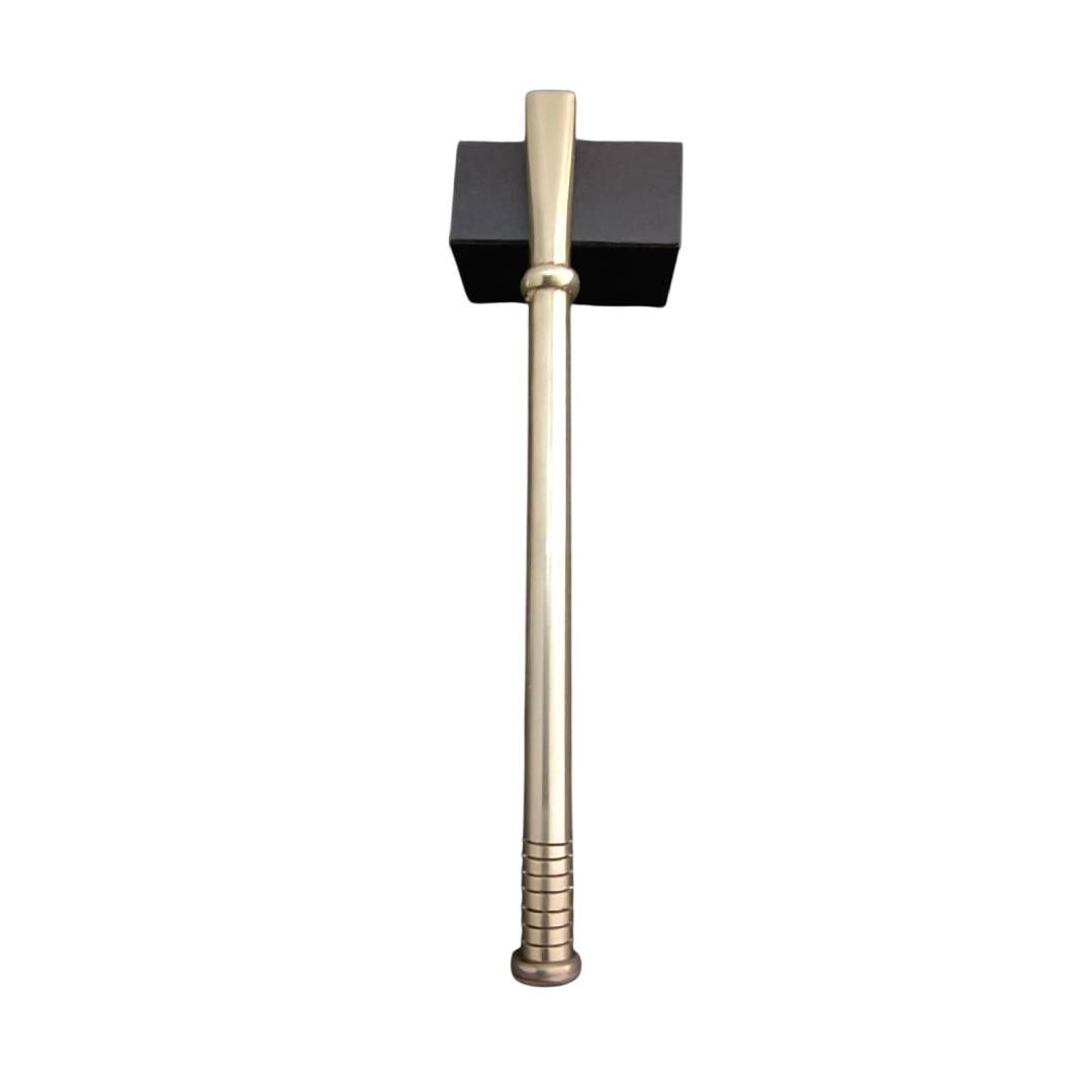 Martillo largo de latón con cabeza cuadrada negra sobre fondo blanco