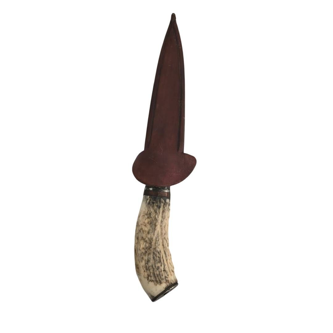Cuchillo rústico con mango de madera oscura y funda marrón sobre fondo blanco.