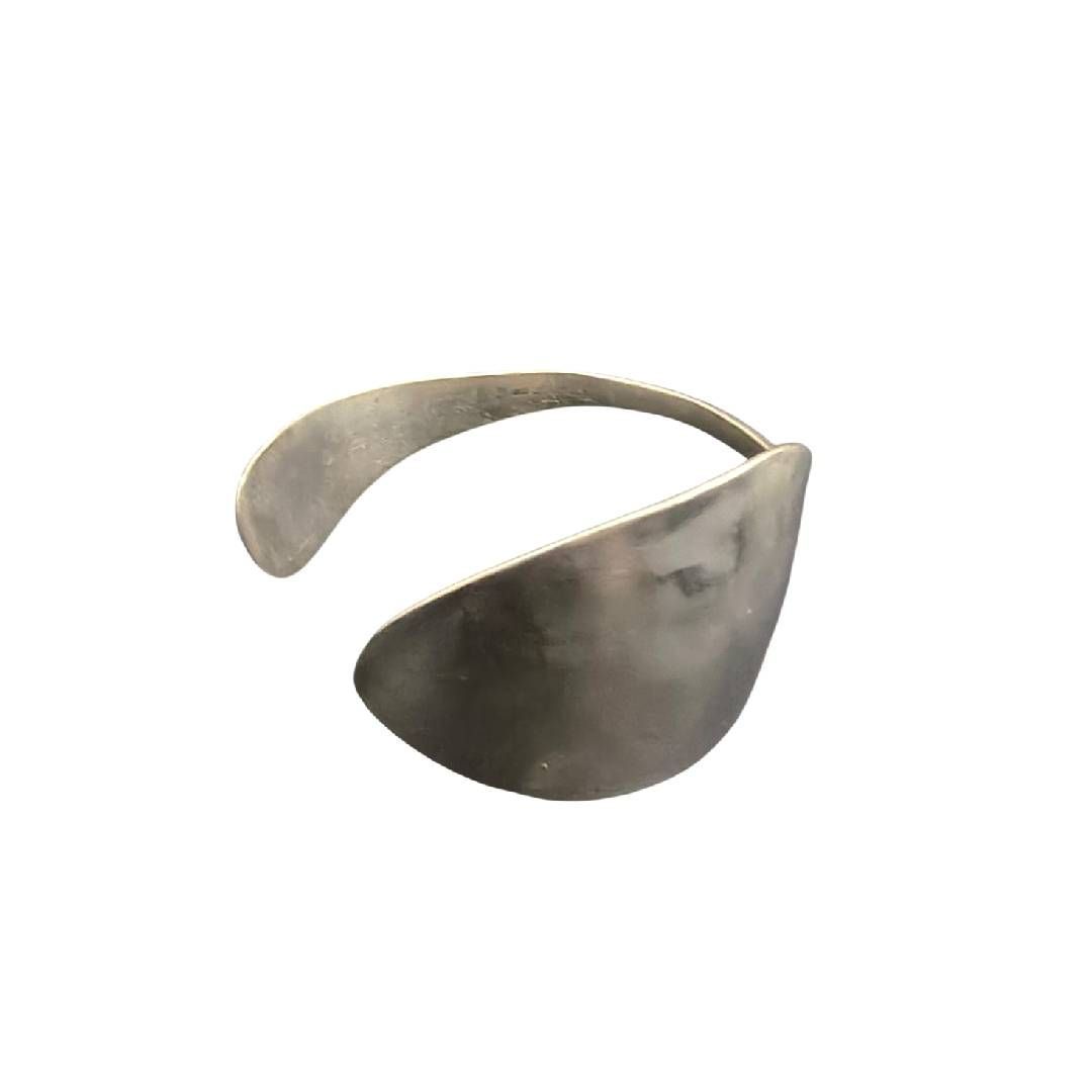 Brazalete de metal gris con diseño curvo y abierto sobre fondo blanco.