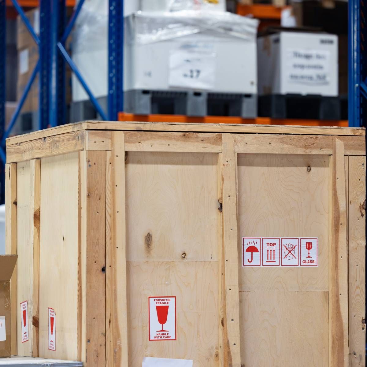 Wooden shipping crate with handling labels in a warehouse aisle