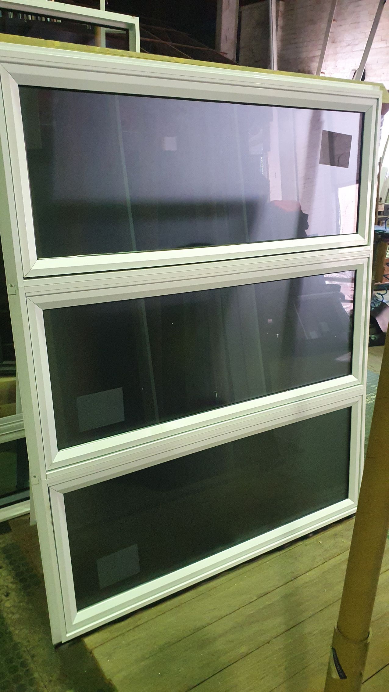 A large window with a white frame is sitting on a wooden floor.