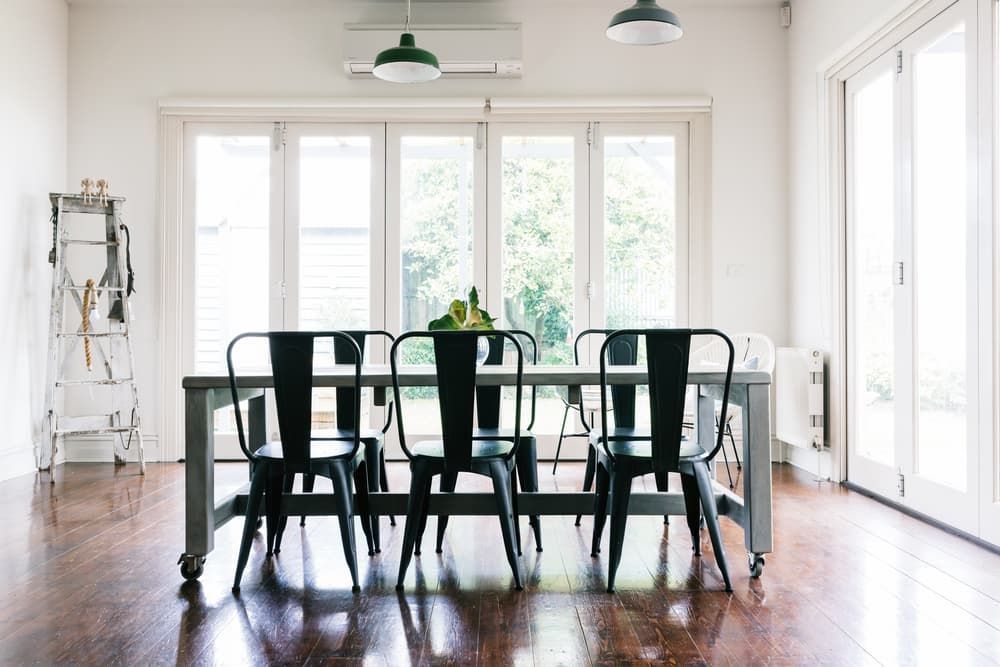 A dining room with a table and chairs and a lot of windows.