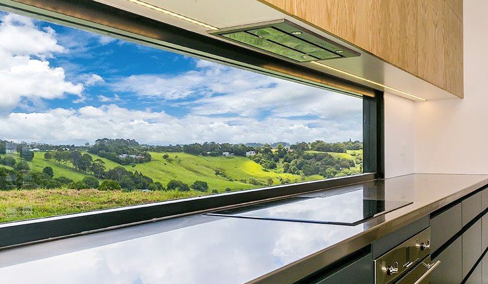 A kitchen with a view of a lush green field through a large window.