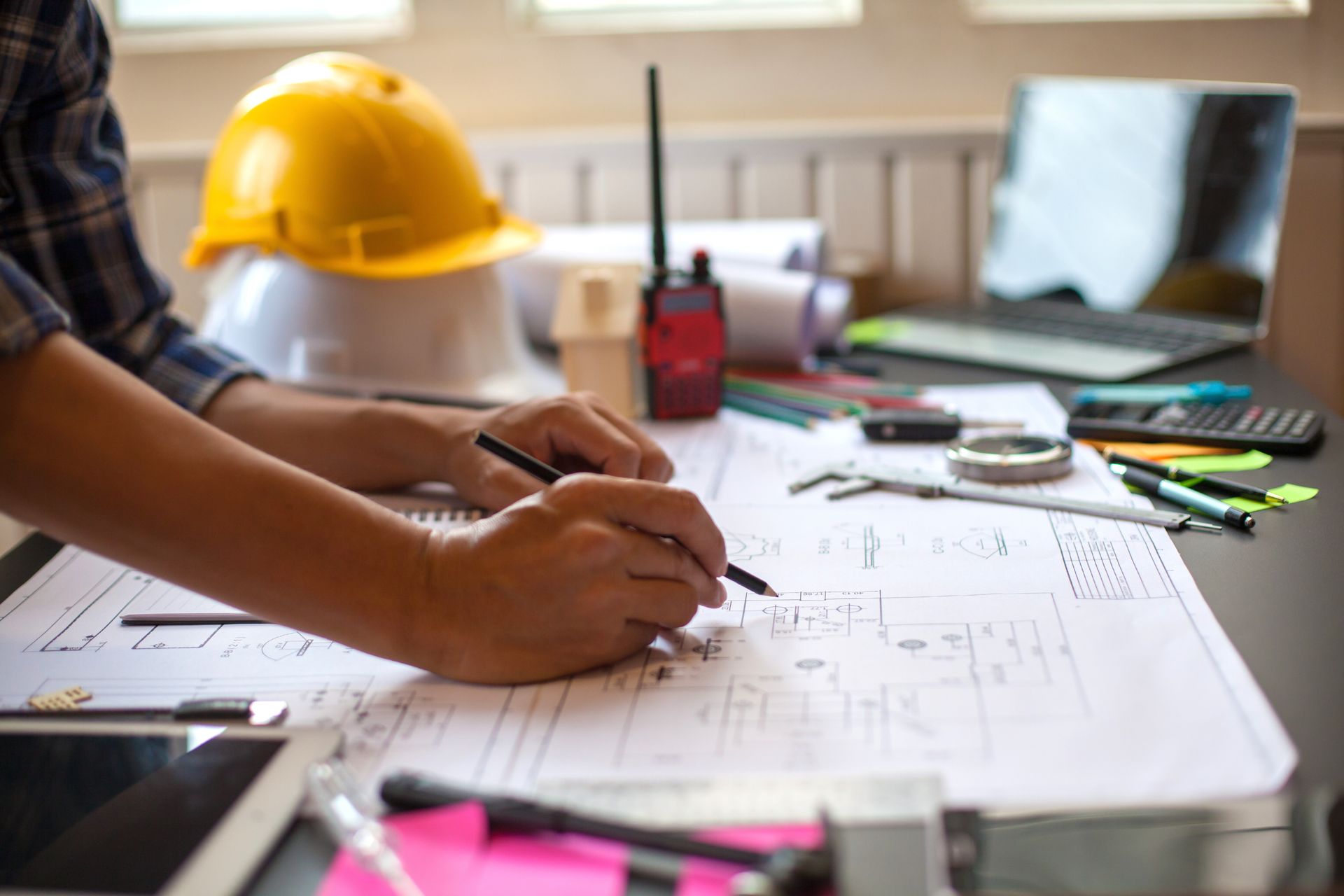 A man is sitting at a desk writing on a blueprint.