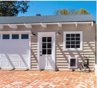 A small house with a garage and a brick driveway