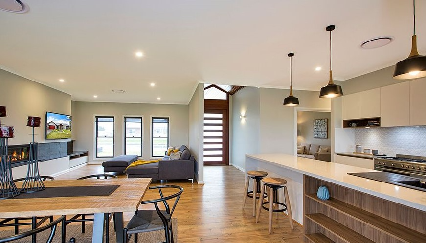 A living room with a couch , table and chairs and a kitchen.