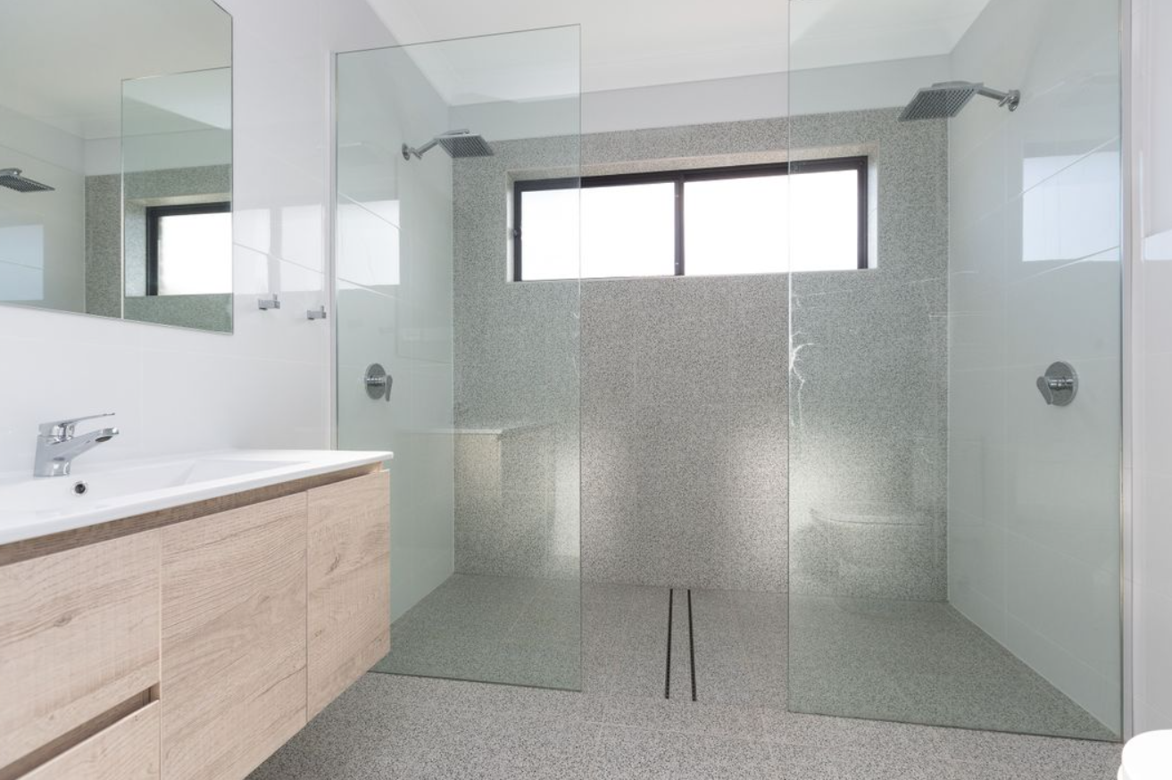 A bathroom with a walk in shower , sink and mirror.
