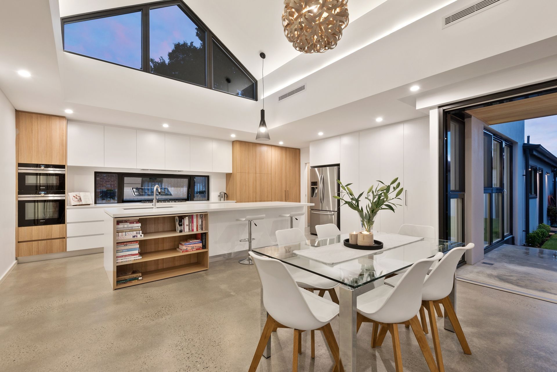 A kitchen and dining room in a house with a glass table and chairs.
