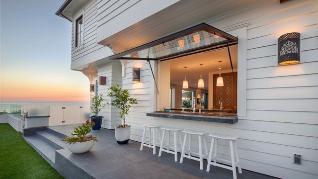 A white house with a bar and stools in front of it.