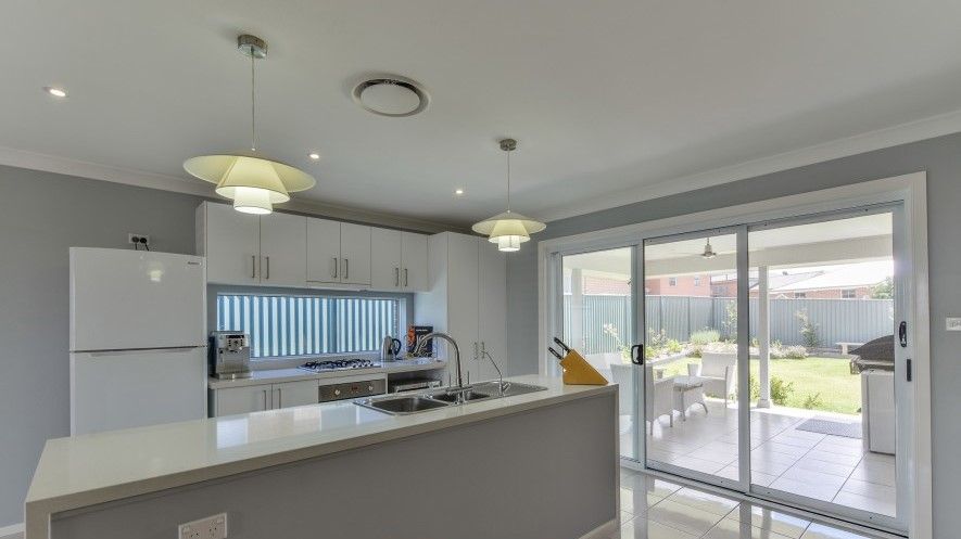 A kitchen with a refrigerator , sink , and sliding glass doors.