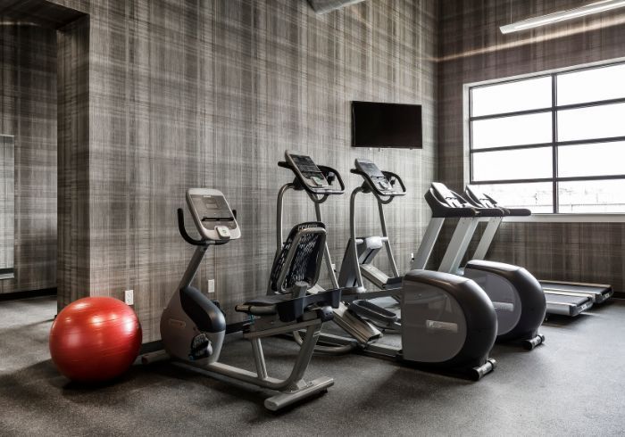 Modern gym with exercise bikes, treadmills, a TV, and a red stability ball
