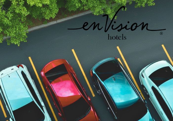 Overhead view of colorful parked cars beside the enVision Hotels logo on pavement