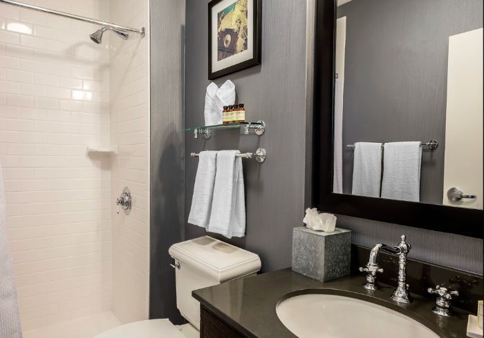 Modern bathroom with shower, vanity, mirror, white towels, and dark gray walls
