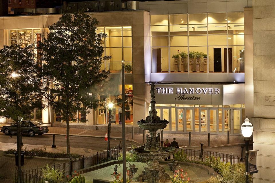 Night view of the Philander building with illuminated windows, trees, and a courtyard fountain