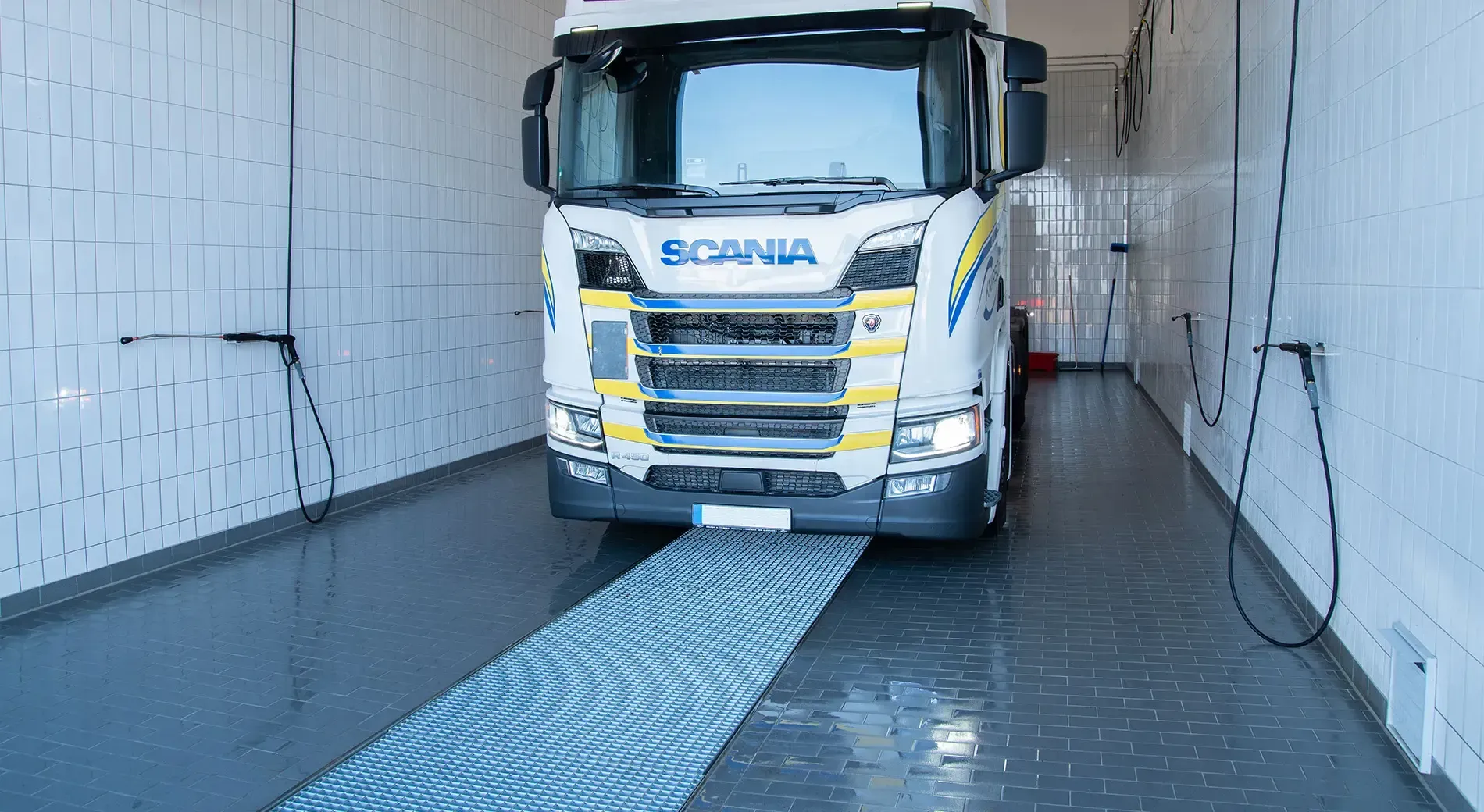 A white truck is driving down a narrow road in a car wash.