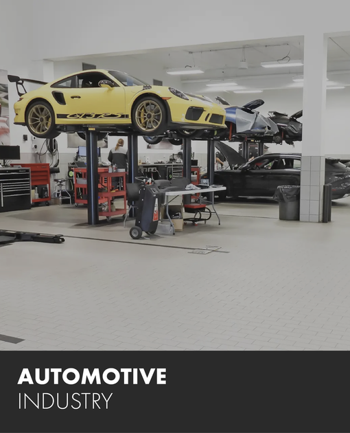 A yellow sports car is on a lift in an automotive industry garage.