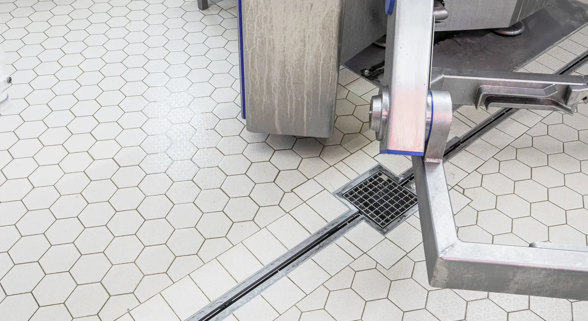 A machine is sitting on a tiled floor next to a drain.