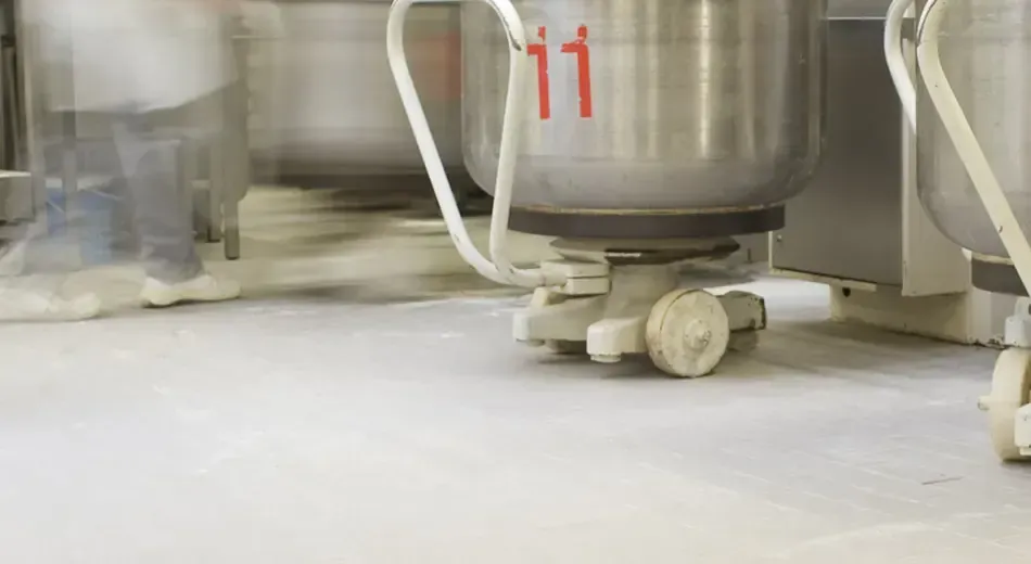 A person is standing next to a mixer in a kitchen.